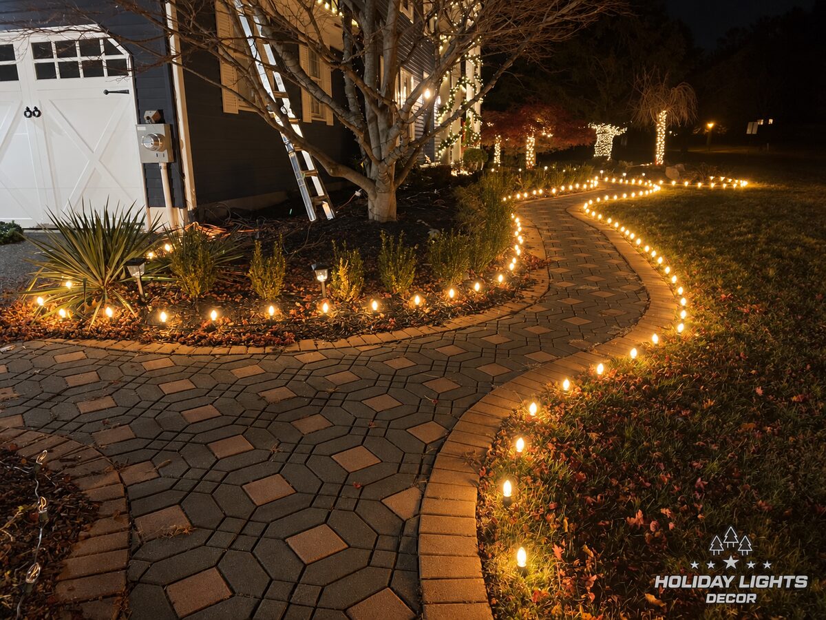 Warm-white bulbs outline both sides of a curved paver walkway at night