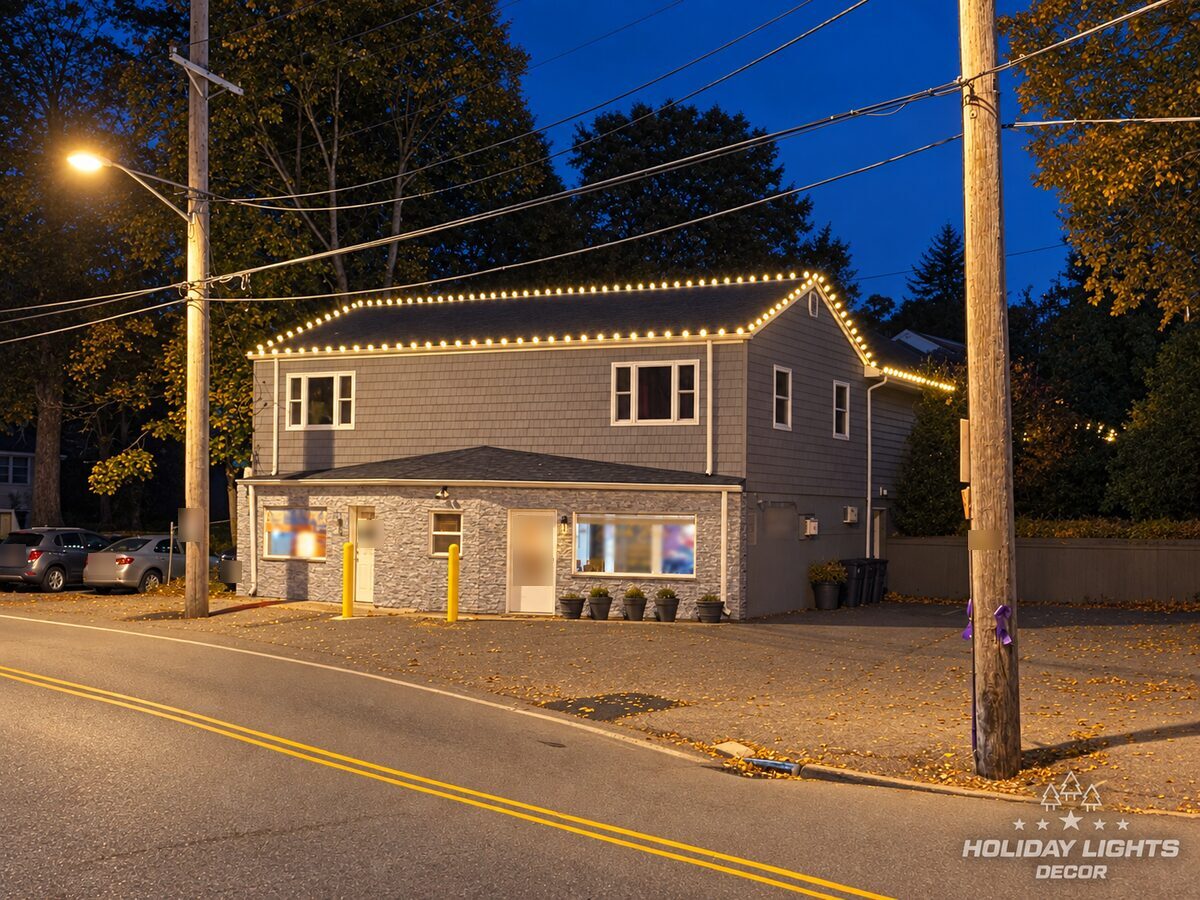 Rear of the same gray commercial building in Little Falls, a two-story section with warm-white bulbs along the roofline