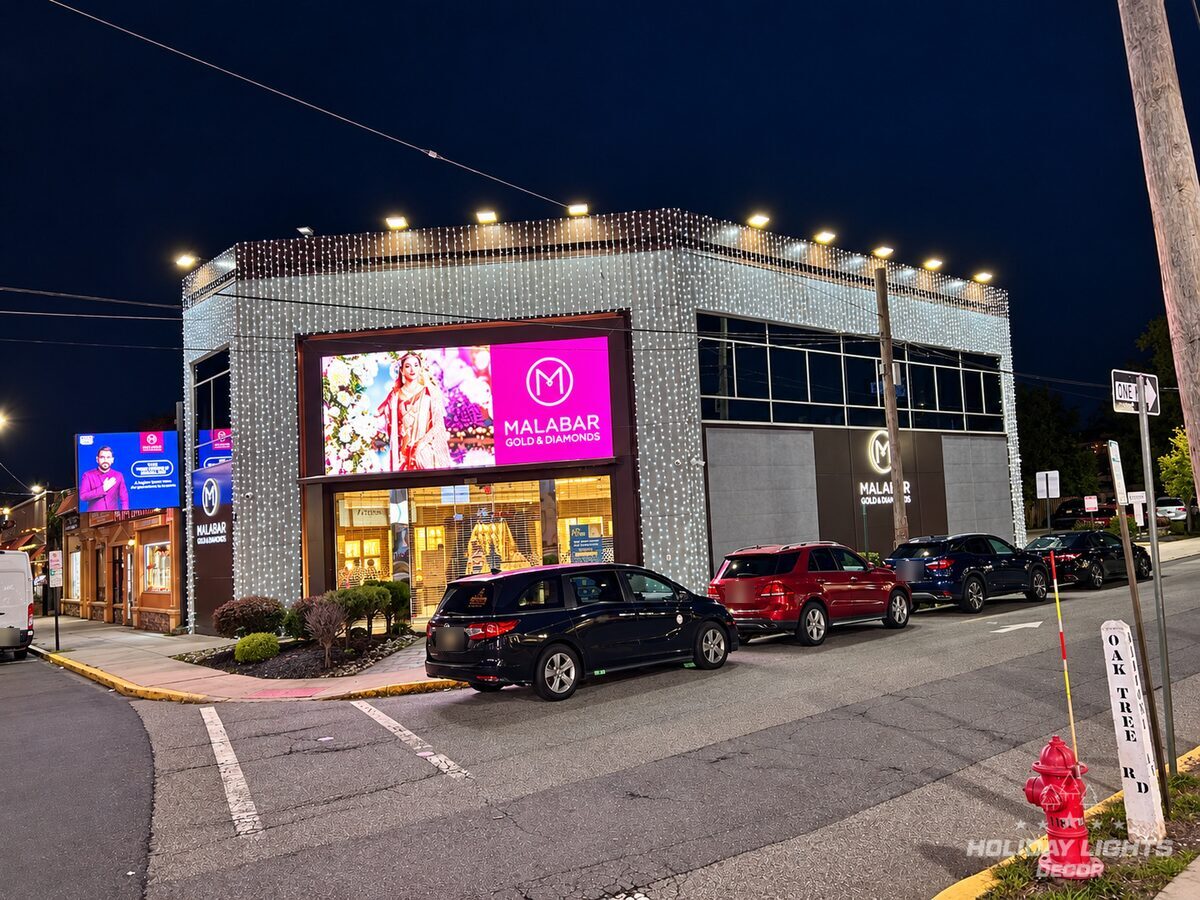 Street corner view of the Iselin jewelry store wrapped in cool white curtain lights on the upper façade