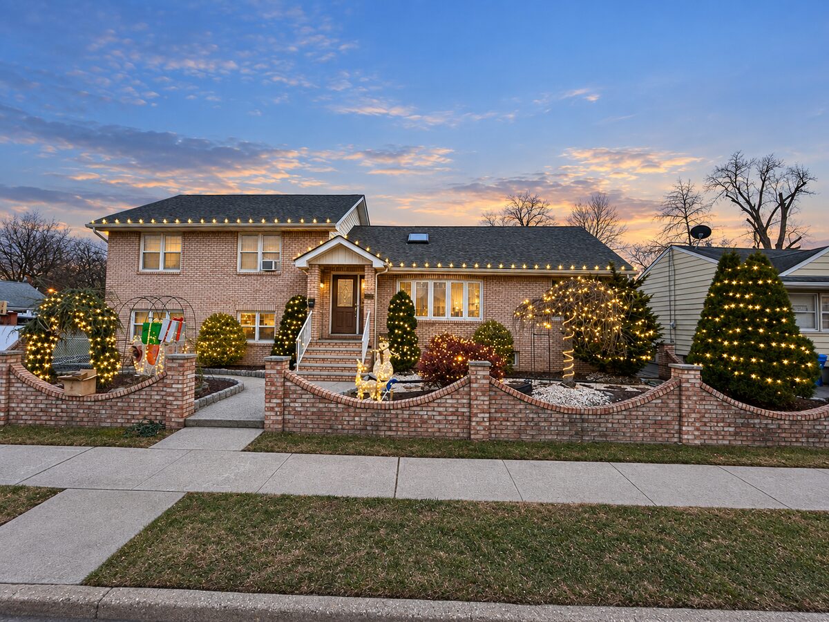 Brick split-level home in Linden with warm-white roofline lights, lit evergreens, shrubs, and yard figures.