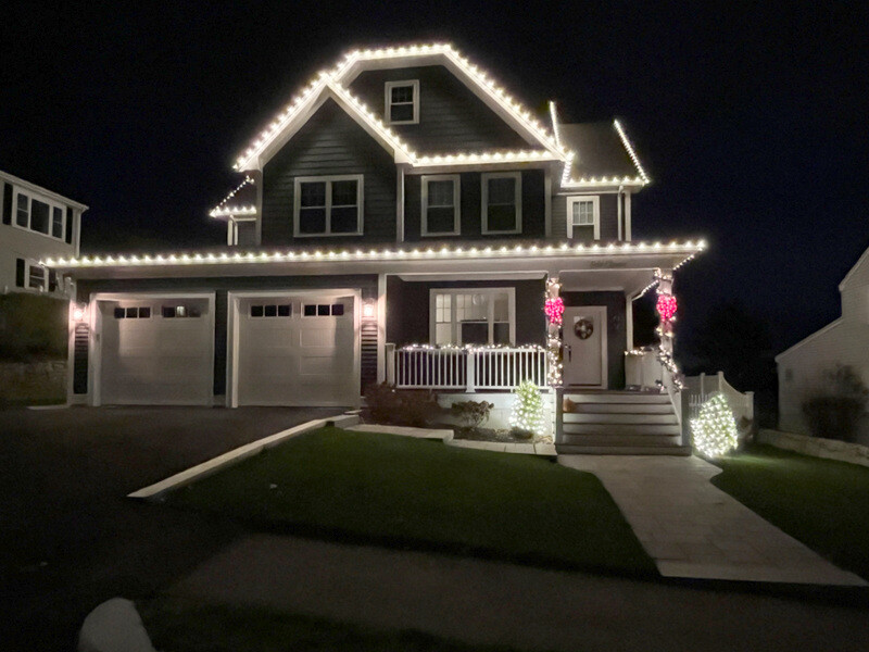 Same home at night with permanent warm-white roofline lights