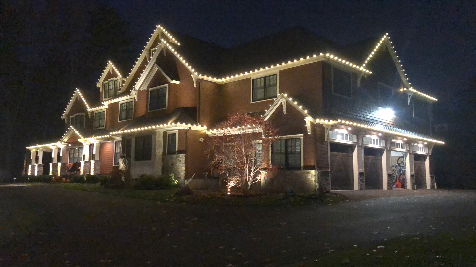 A commercial plaza decorated with Christmas lights at night